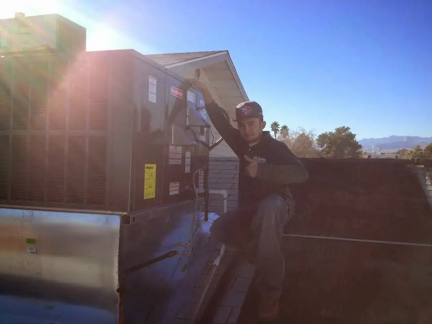HVAC technician performing AC Tune-Up on a rooftop unit in Reedley