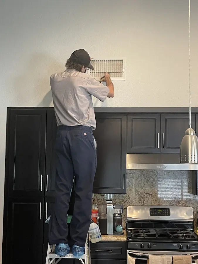 Technician inspecting an air vent during HVAC service in Reedley